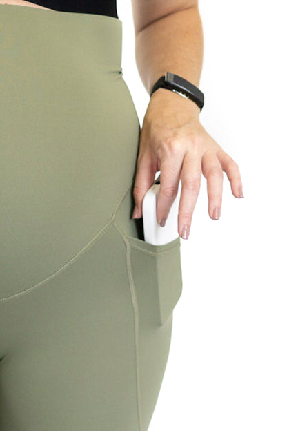 Hand in a fitness tracker using a computer mouse while wearing maternity leggings