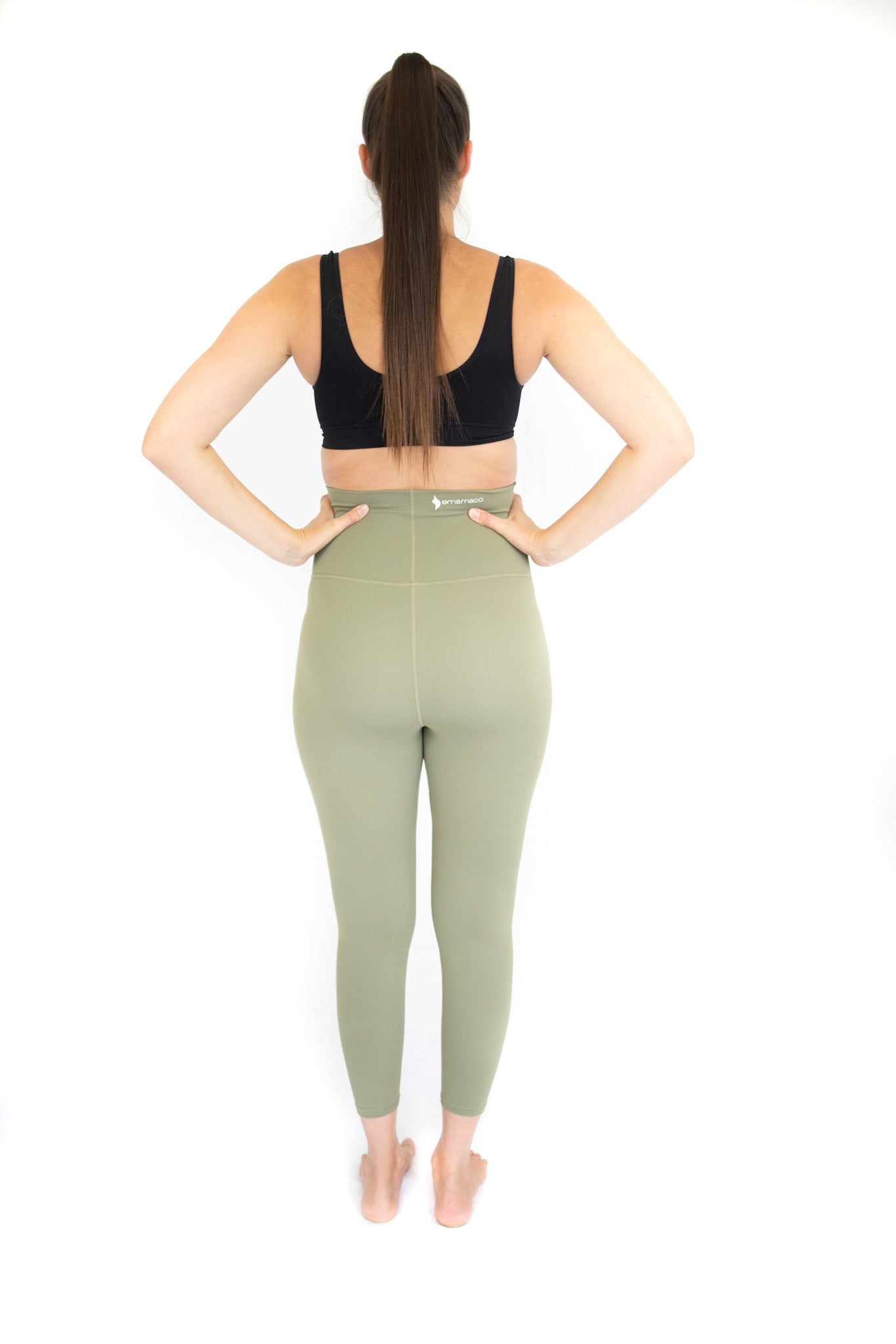 Woman’s back in black sports bra and olive Emamaco maternity leggings for active wear