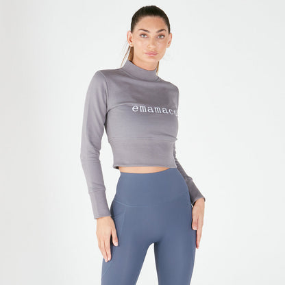 Woman in a crisp charcoal grey cropped long-sleeve top and blue high-waisted leggings