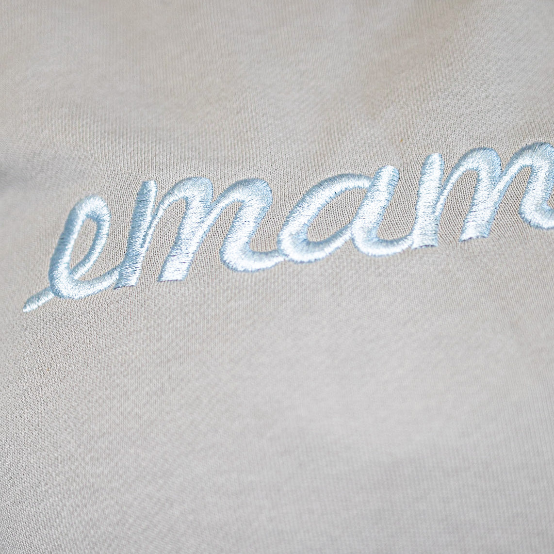 Embroidered cursive text emam on light fabric of cropped sweat maternity activewear