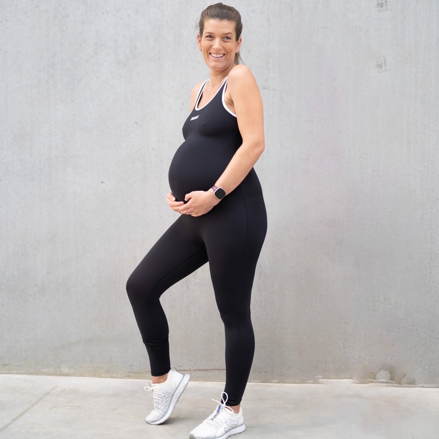 Pregnant woman in black athletic outfit showcasing Emama Maternity Bodysuit designed for comfort