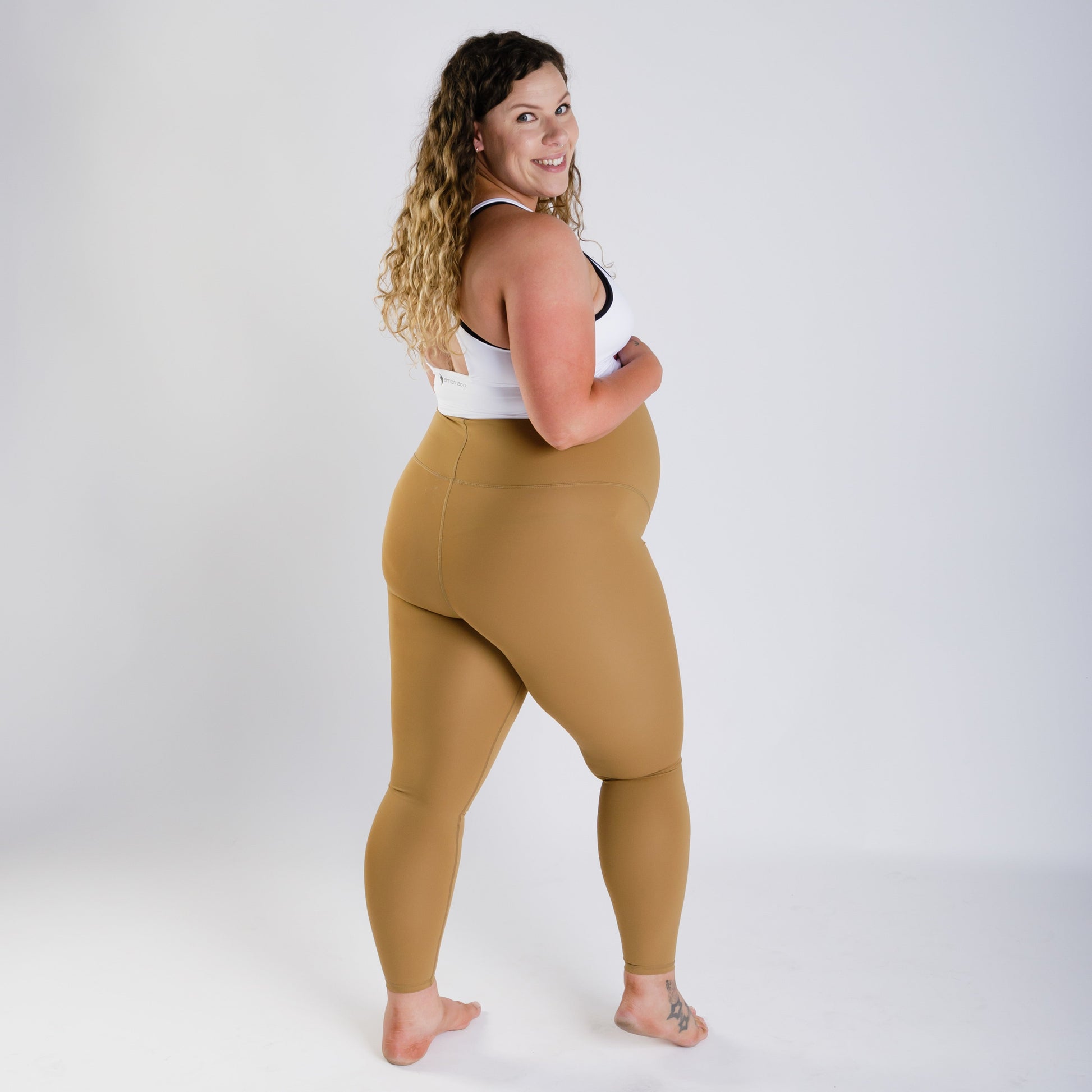 Woman in white top and mustard leggings showcasing Emama Maternity Leggings on final sale