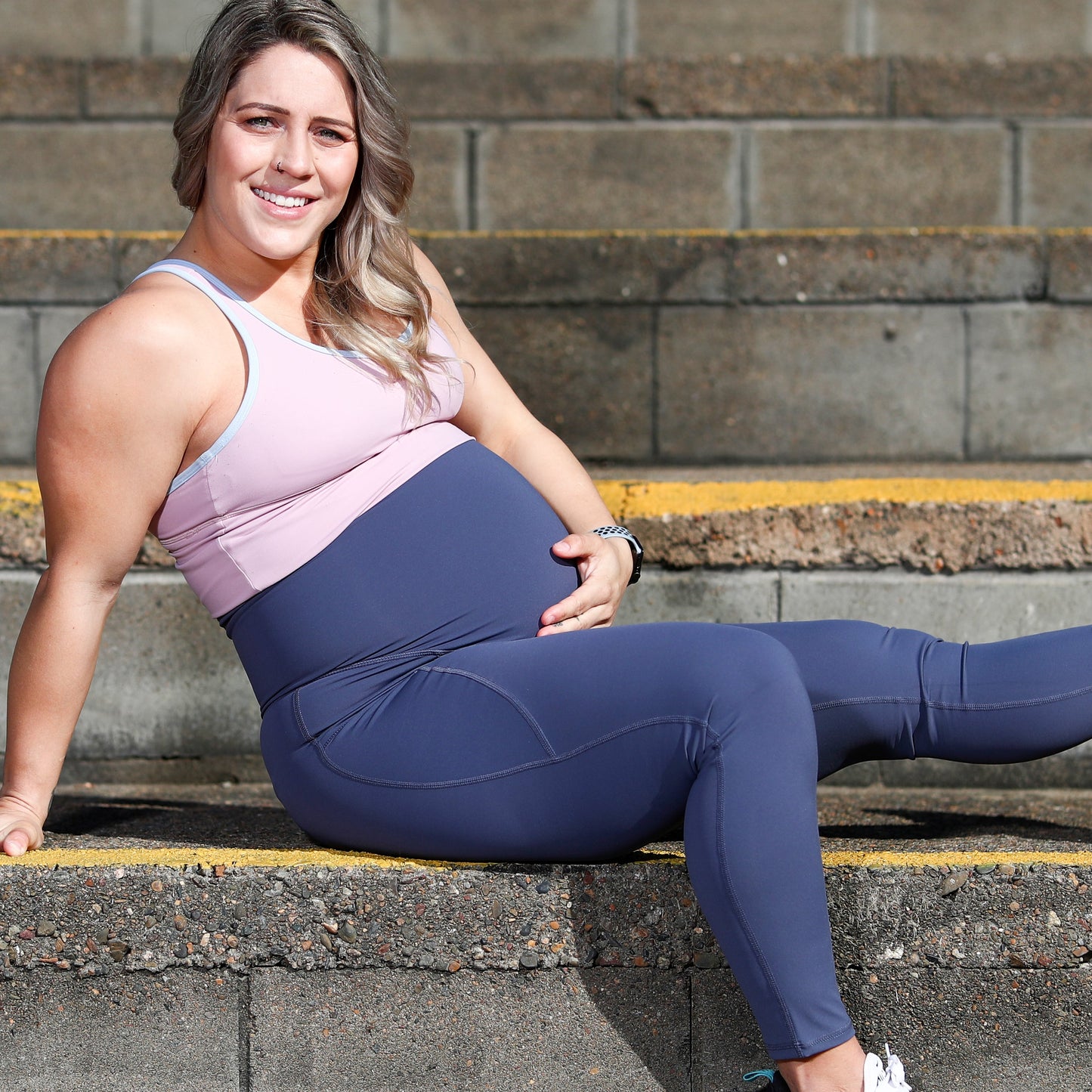 Smiling woman in Emama Maternity Leggings Full Length sitting on concrete steps