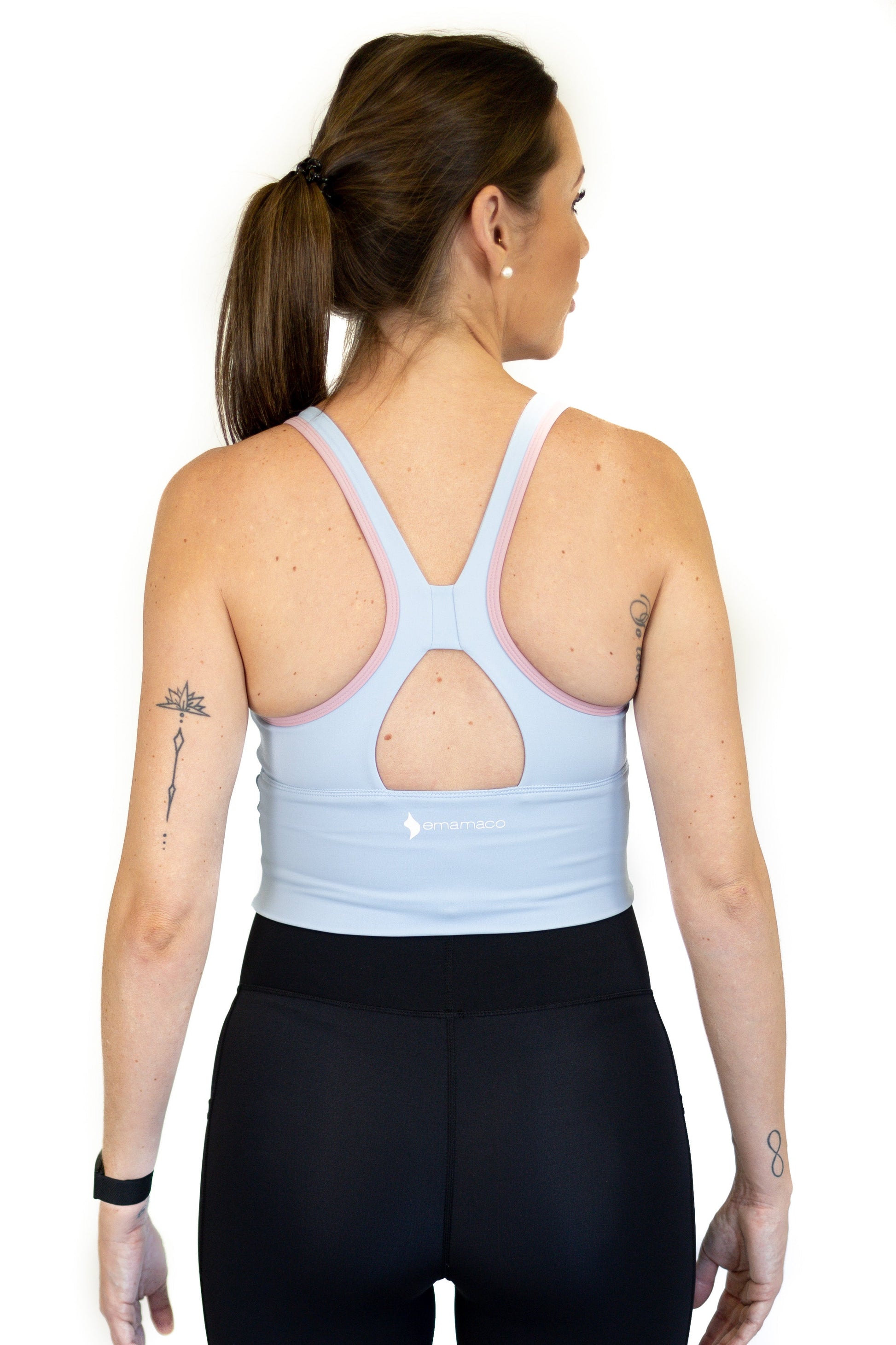 Woman in light blue racerback sports top and black leggings showcasing emamaco’s long line design