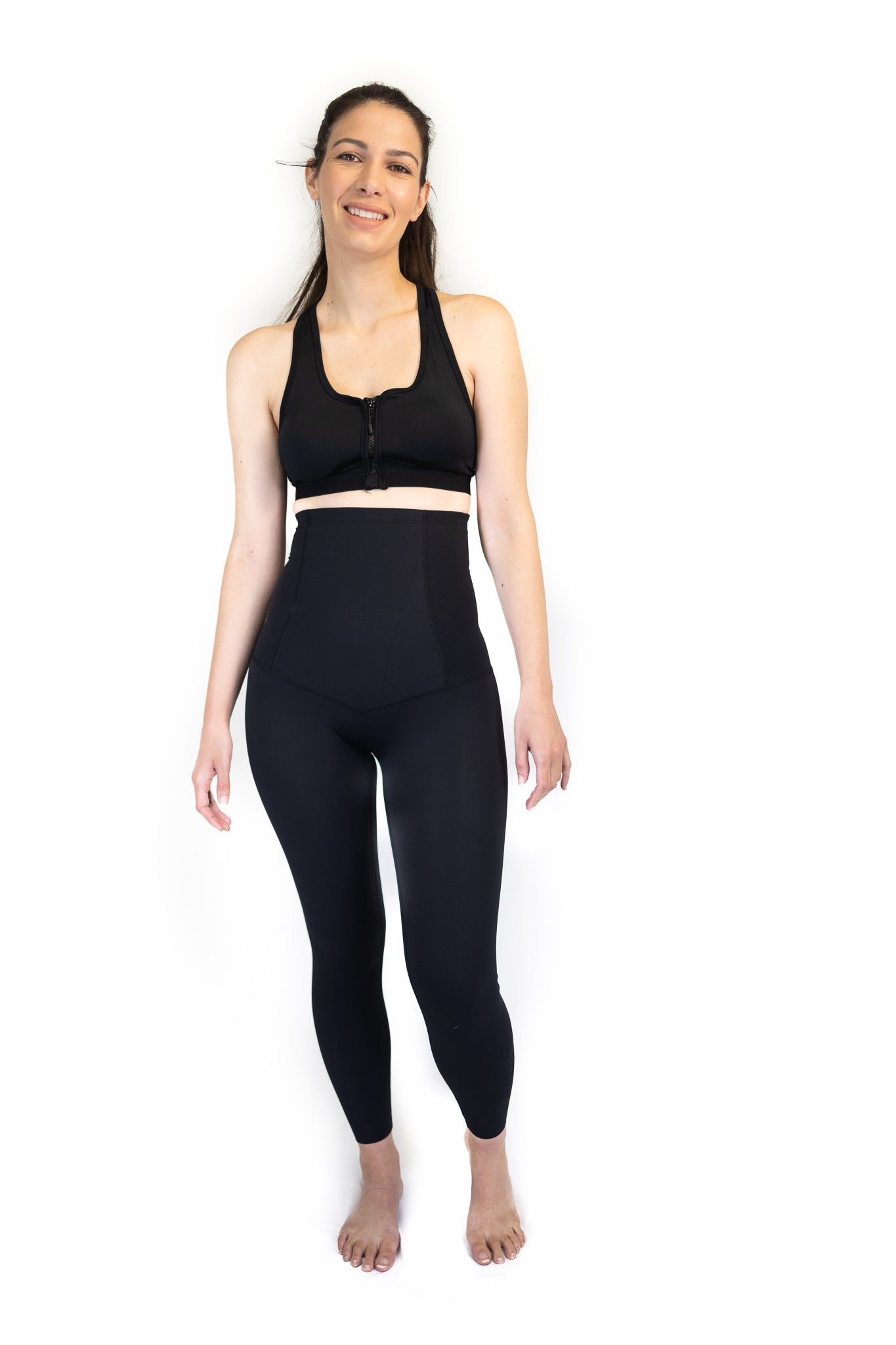 Woman in black sports bra and high-waisted leggings for pregnancy recovery