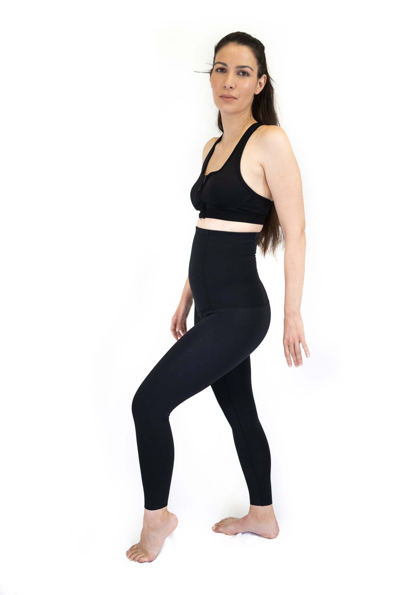 Woman in black sports bra and high-waisted leggings for pregnancy recovery comfort