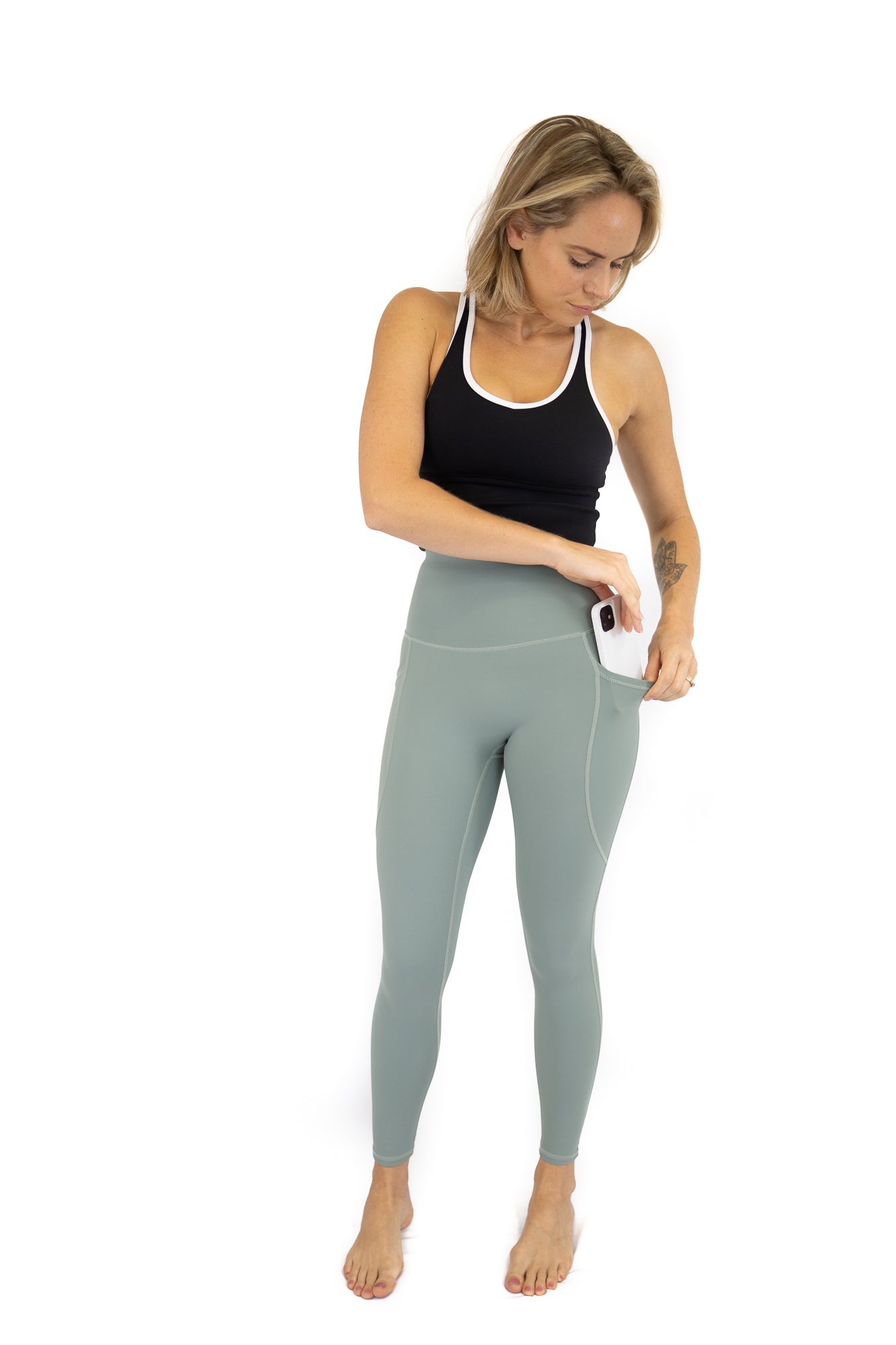 Woman in Shaper Move Leggings, holding smartphone during final sale with limited sizes