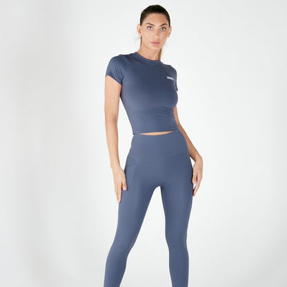 Woman in blue-gray athletic crop top and leggings made of Supaflex material activewear