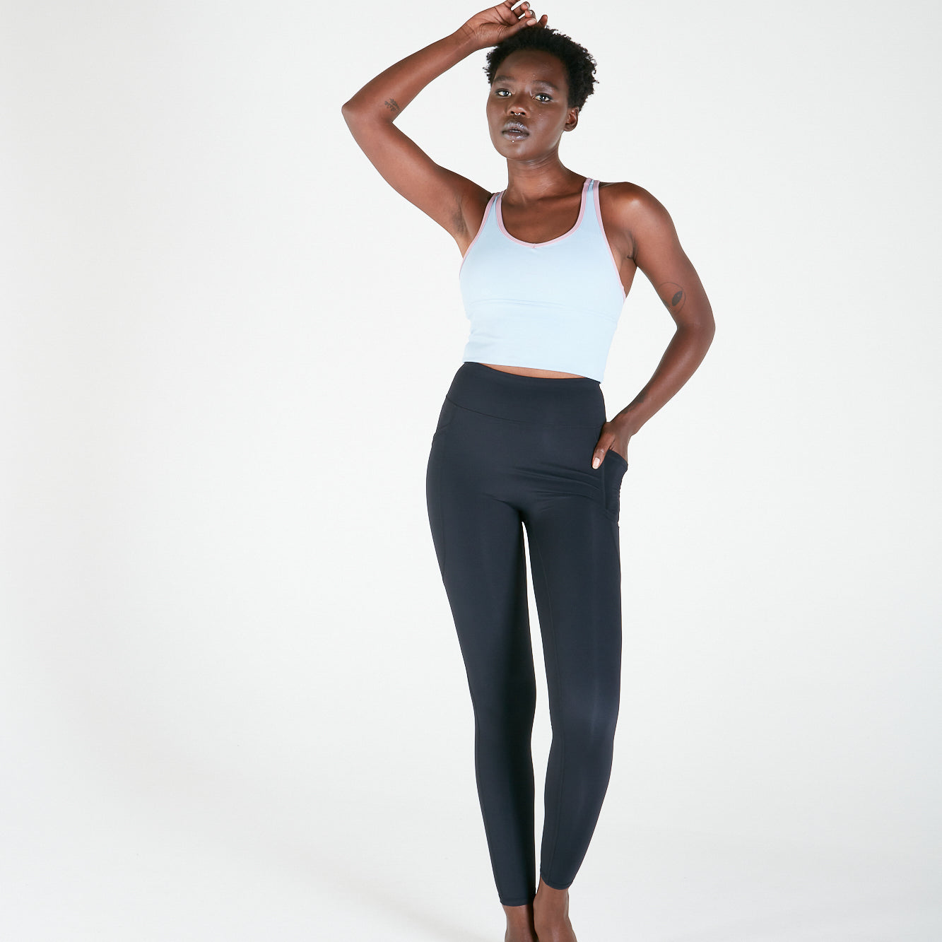 Woman in white tank top and dark leggings showcasing Vibe Leggings with regular fit